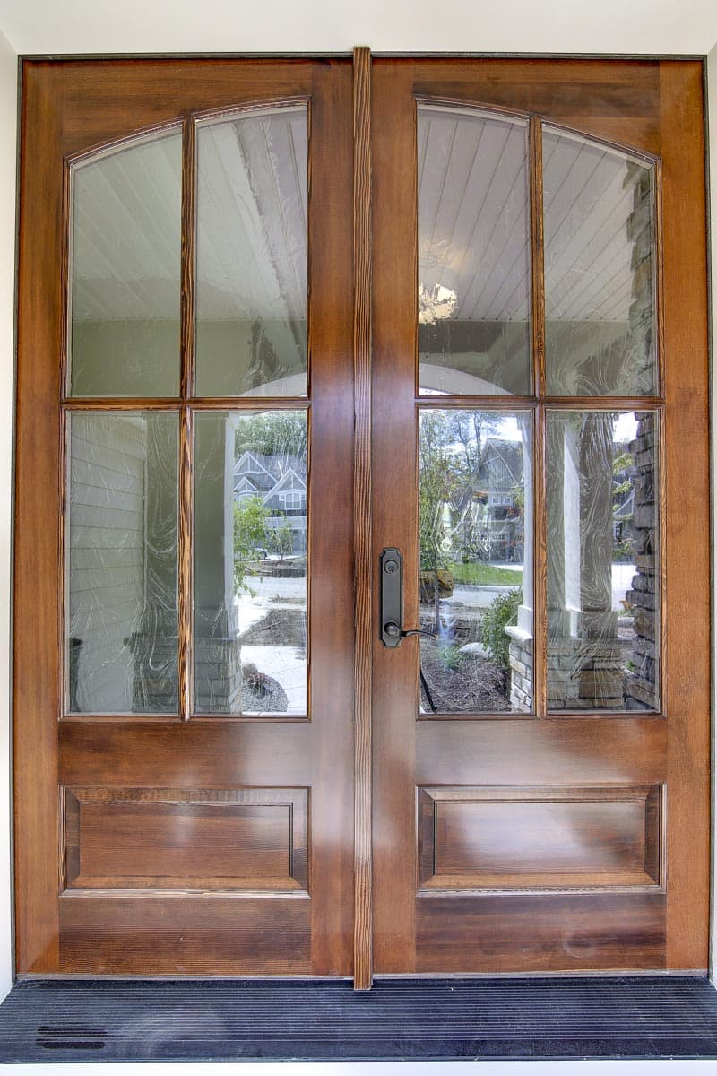 Double entry doors with arched glass transoms and multi-pane sidelights. Visible paneled base.