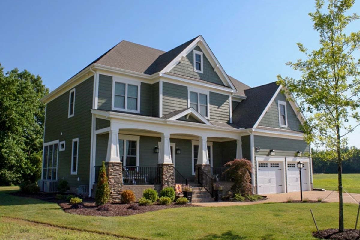 House plan exterior of a two-story home with a wraparound porch, stone accents, and a three-car garage.