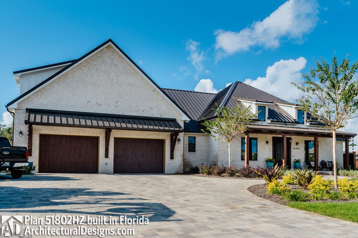 House plan exterior: Modern Farmhouse style with white brick, metal roof, two-car garage, and covered front porch.