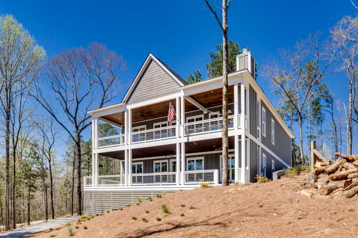Modern Farmhouse style house plan exterior with three stories, multiple covered porches, gabled roof, and vertical siding.