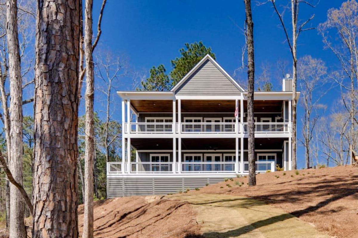 Modern farmhouse house plan exterior with three-story balconies, gables, and horizontal siding.