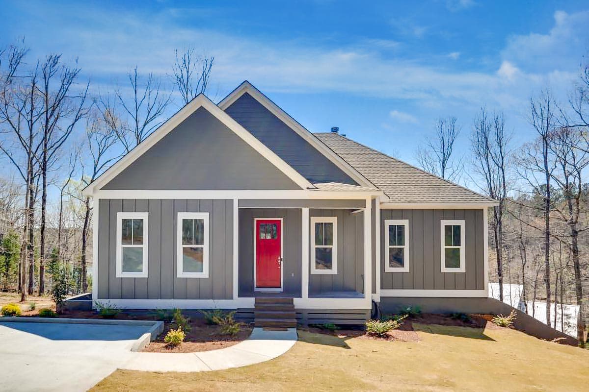 House plan exterior. One-story house with gabled roof, front porch, and vertical siding. Features a red front door and multiple windows.