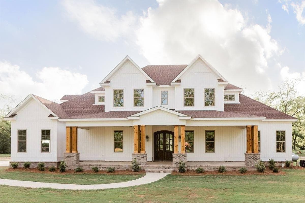 House plan exterior featuring a two-story farmhouse style with a front porch, gables, and wood-wrapped columns supporting the roof.