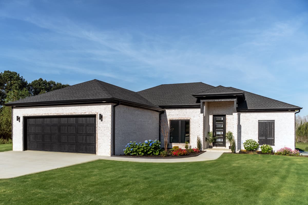 House plan exterior. Modern, one-story home with a garage, gabled roof, and covered entry. The home has a brick exterior.