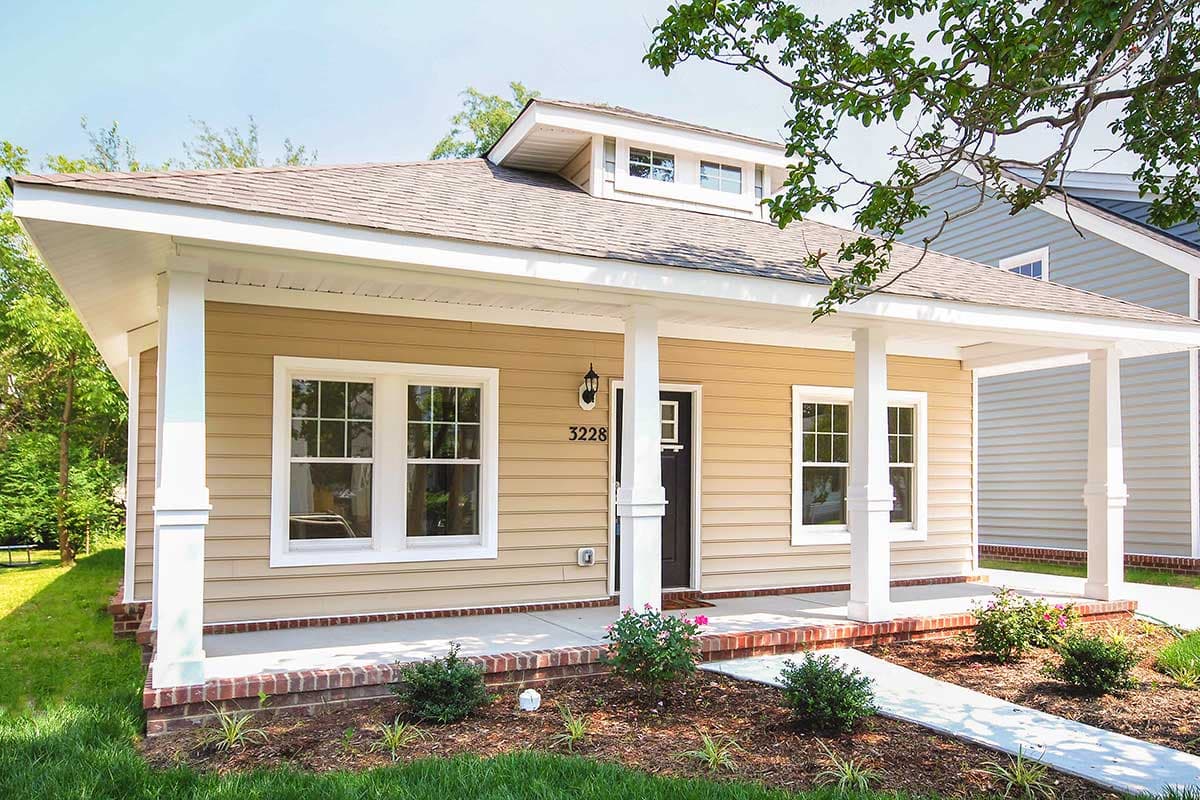 House plan exterior with Craftsman style. Features include a front porch with pillars, gabled roof, and dormer windows on a single-story structure.