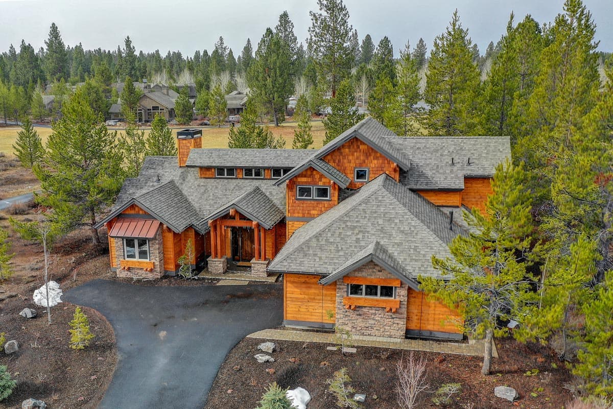 House plan exterior: Modern lodge style, timber and stone accents, complex rooflines, prominent gabled entrance, and multiple dormers.