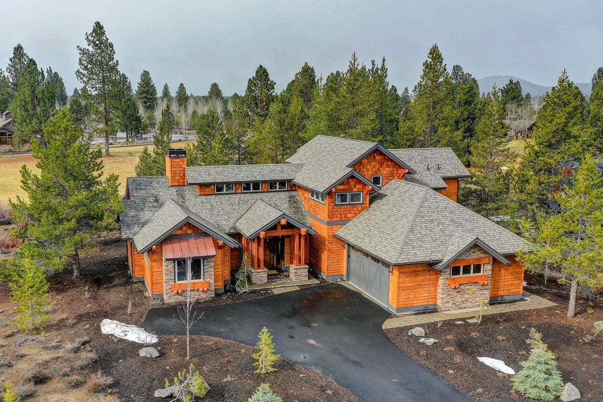 House plan exterior featuring a multi-level roofline, wood siding, stone accents, and a side-entry garage.