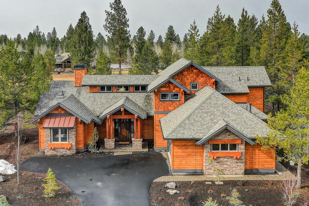 Modern lodge style house plan exterior with wood siding, stone accents, and multi-level rooflines.