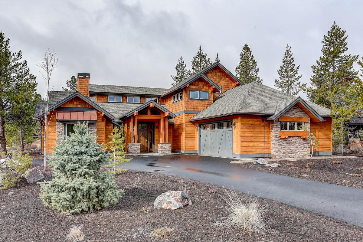 House plan exterior with wood siding, stone accents, gable roof, covered entryway, and attached garage.