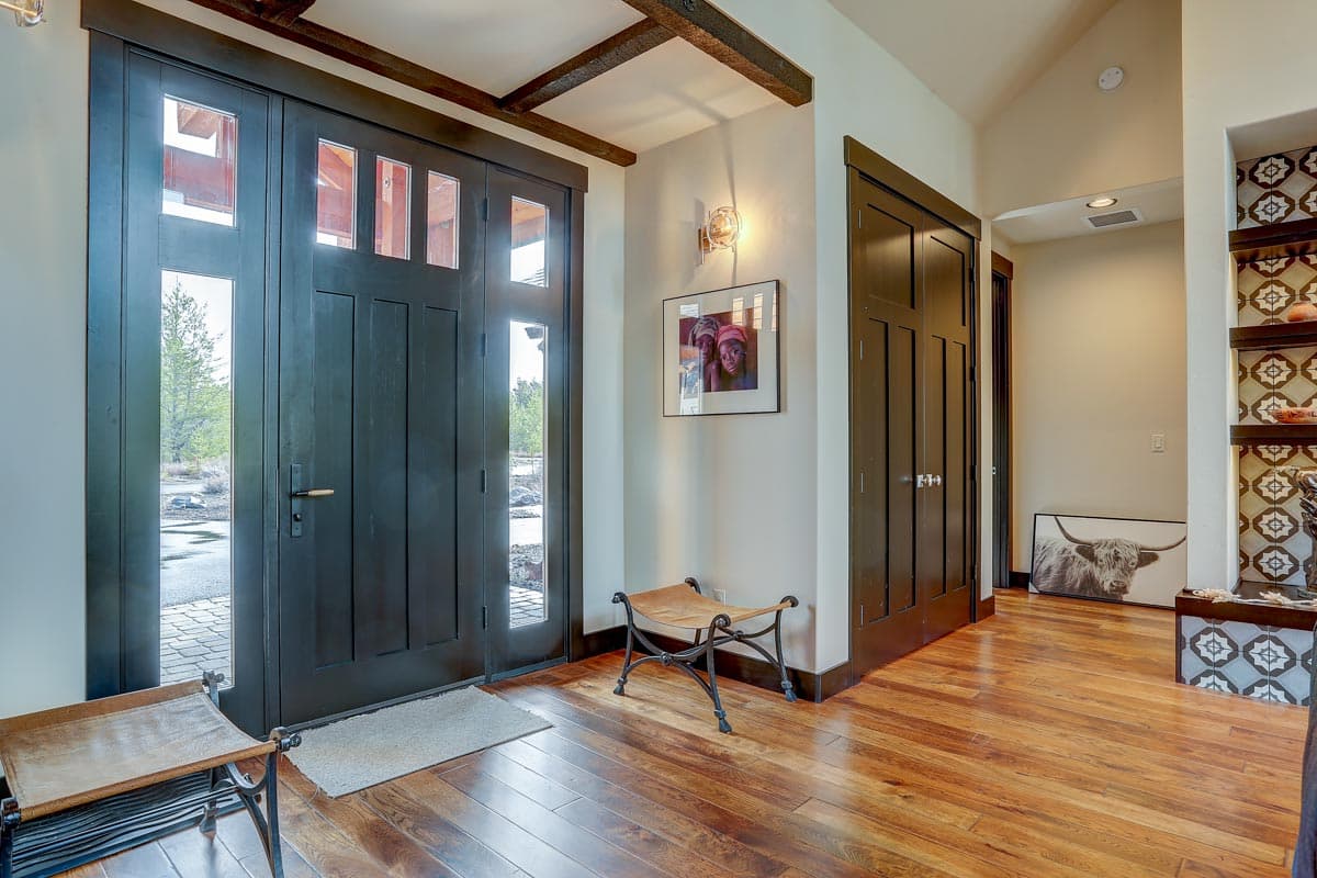 Entryway with double dark wood doors, exposed ceiling beams, and hardwood floors.