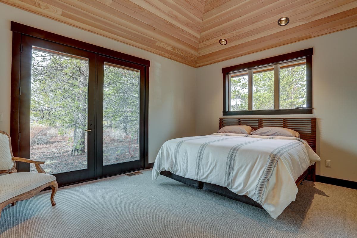 Bedroom with paneled wood ceiling, double glass doors, and a horizontal slatted headboard.