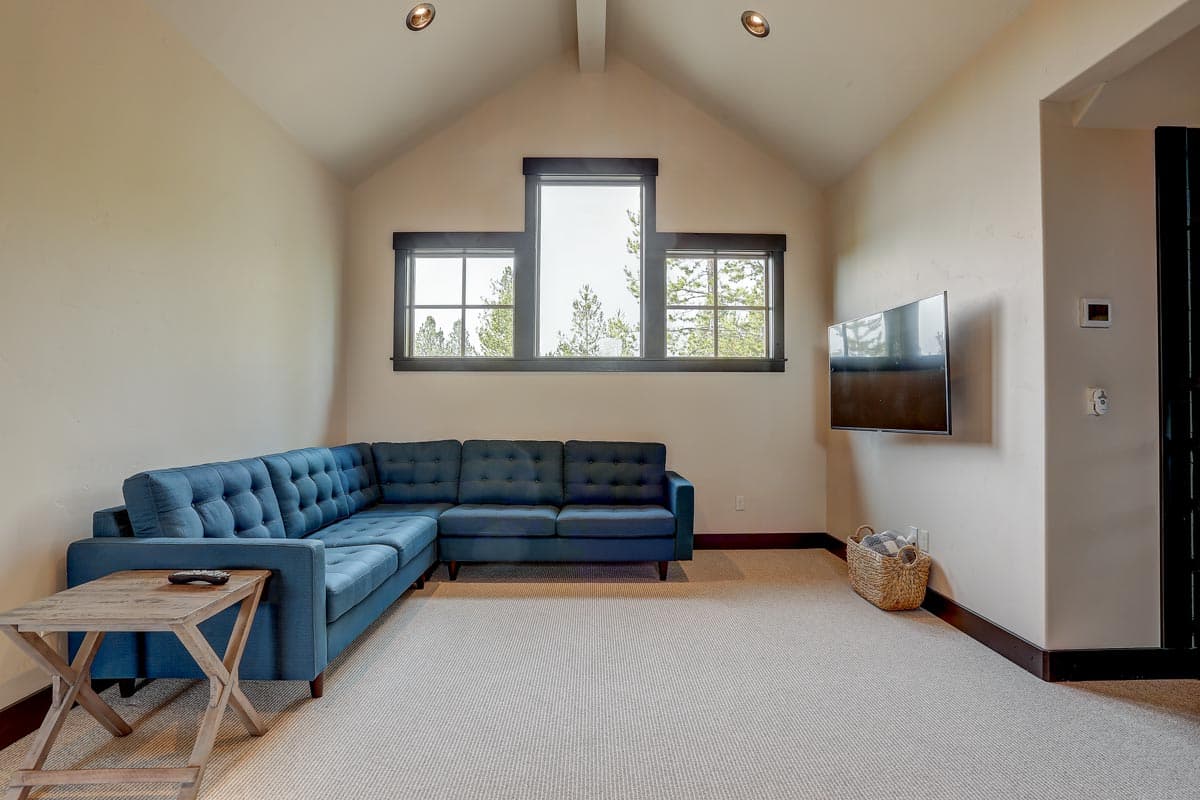 Interior rendering of a living area with vaulted ceiling, sectional sofa, and wall-mounted television.