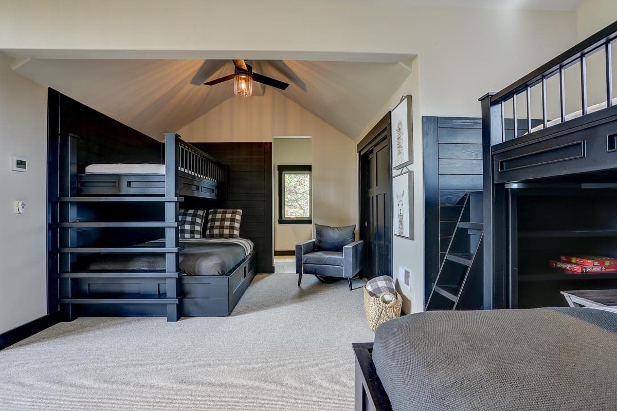 Bedroom with bunk beds, vaulted ceiling, ceiling fan, and armchair.