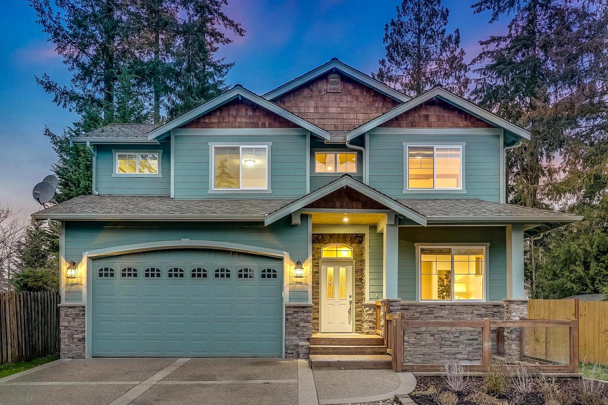 House plan exterior: Two-story home with a prominent gable, covered entry with stone accents, and a side-facing garage.