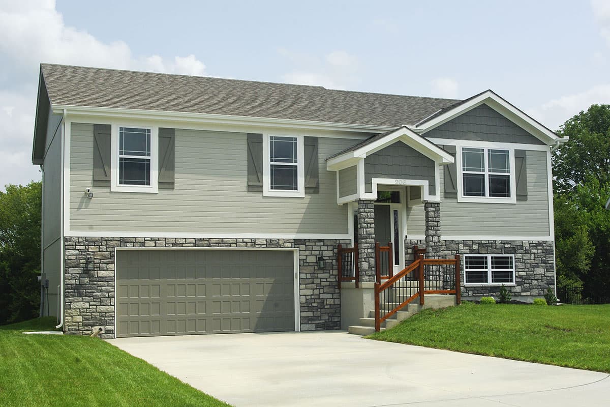 House plan exterior. Two-story home with a gabled roof, stone veneer on the lower level, and a covered front entry porch with columns.
