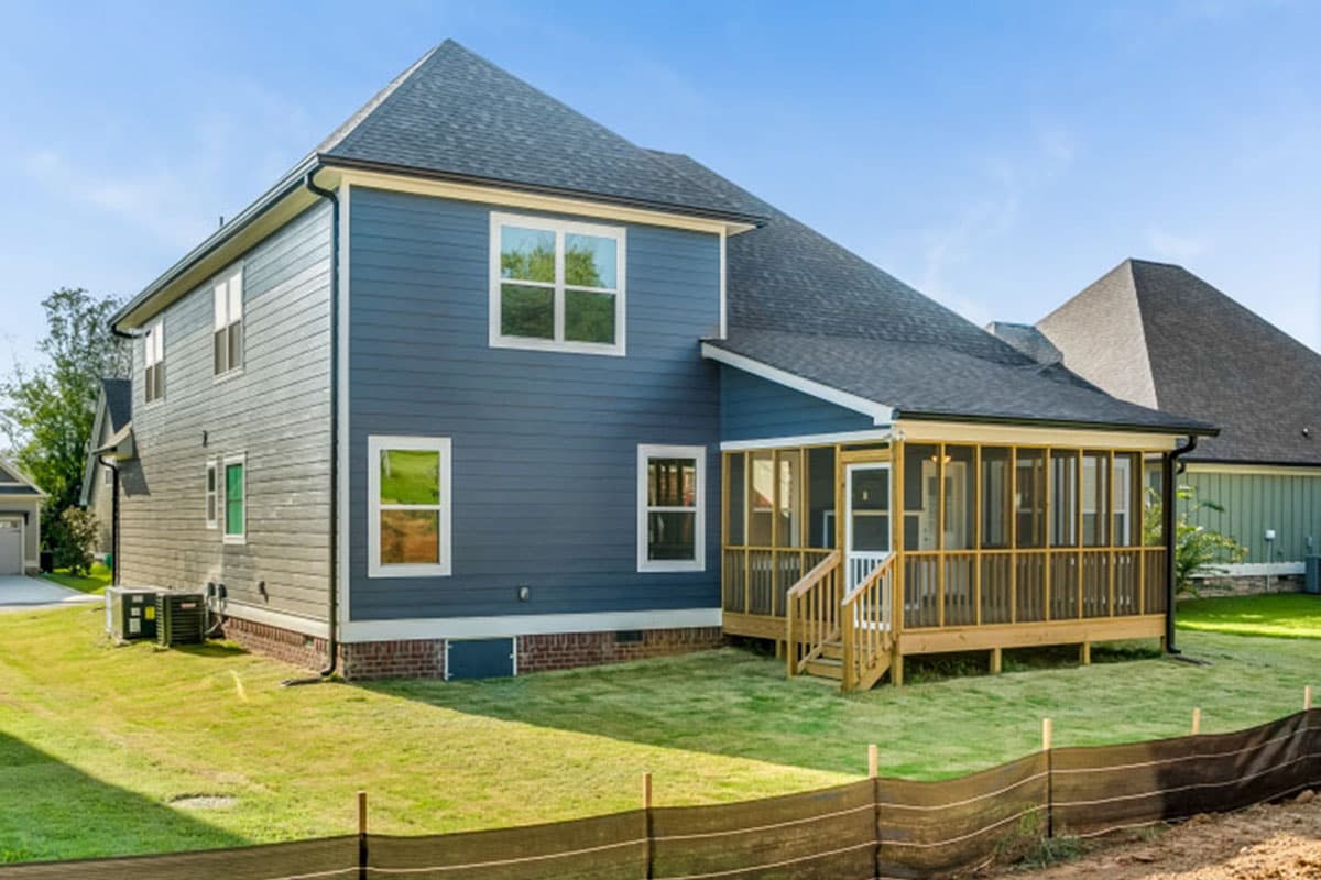 Two-story house exterior with blue siding, gabled roof, and screened-in back porch with wooden deck.
