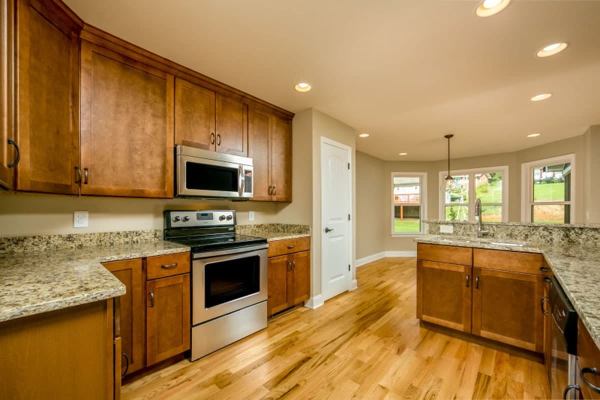 Kitchen with wood cabinets, granite countertops, stainless steel appliances, and a sink overlooking the backyard.