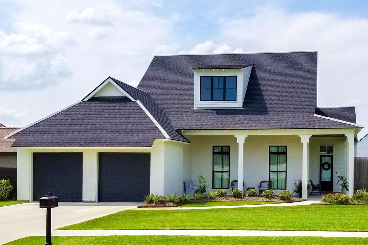 House plan exterior: Two-story modern farmhouse with side-entry garage, dormer, and covered porch with white columns.