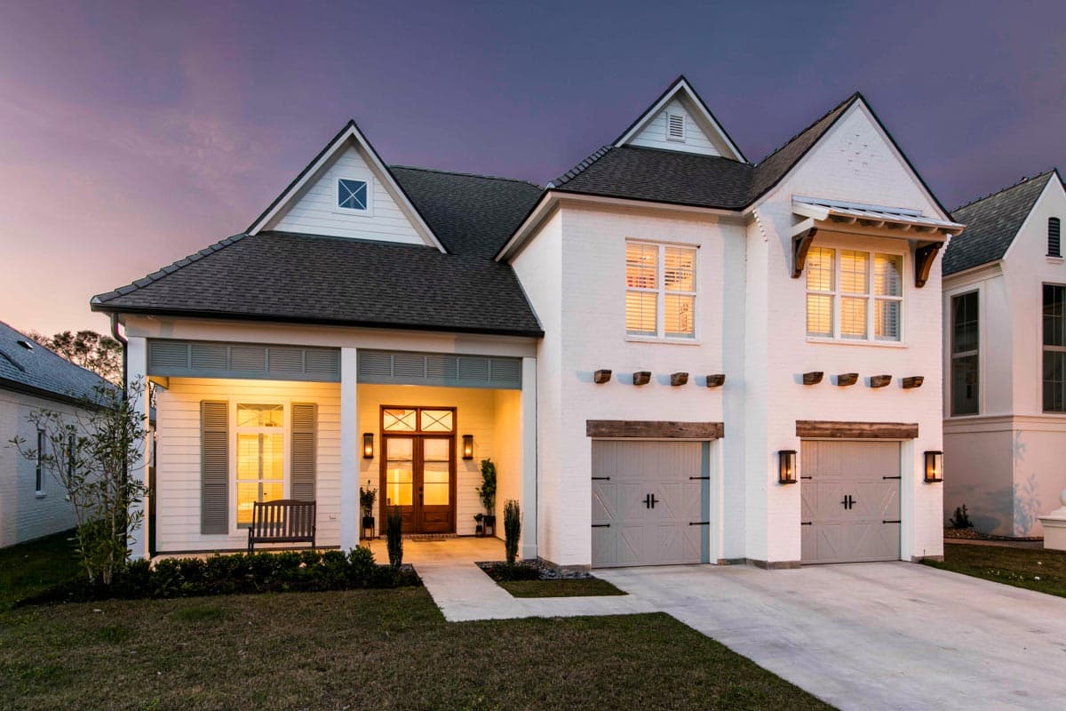 House plan exterior. Two-story Modern Farmhouse with gabled roof, front porch, and two-car garage. Dormers and decorative beams accent the facade.