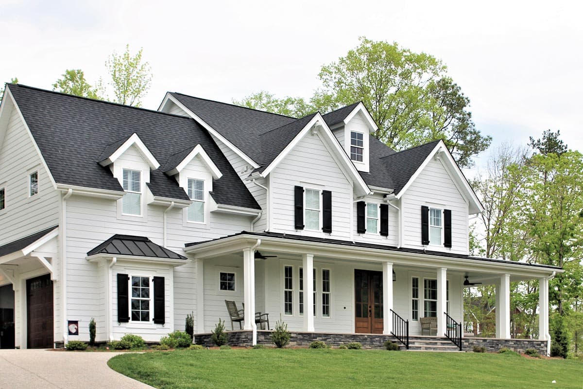 Modern Farmhouse style house plan exterior, two stories, with wrap-around porch, dormers, and a gabled roof.