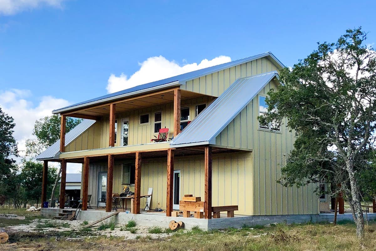 House plan exterior: two-story dwelling with a standing seam metal roof, covered decks, and vertical siding.