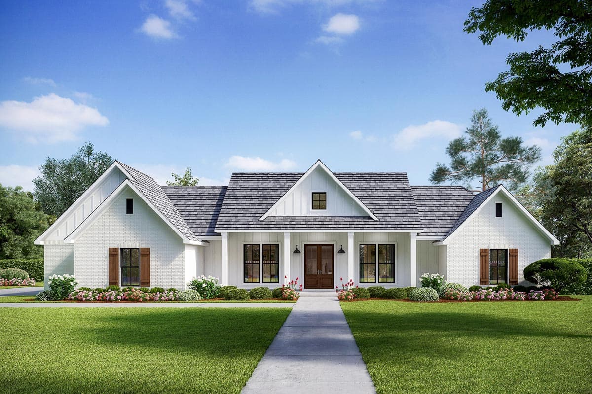 A white, brick-faced farmhouse with a gray roof, symmetrical design, and a concrete pathway leading to the front door, on a sunny day.