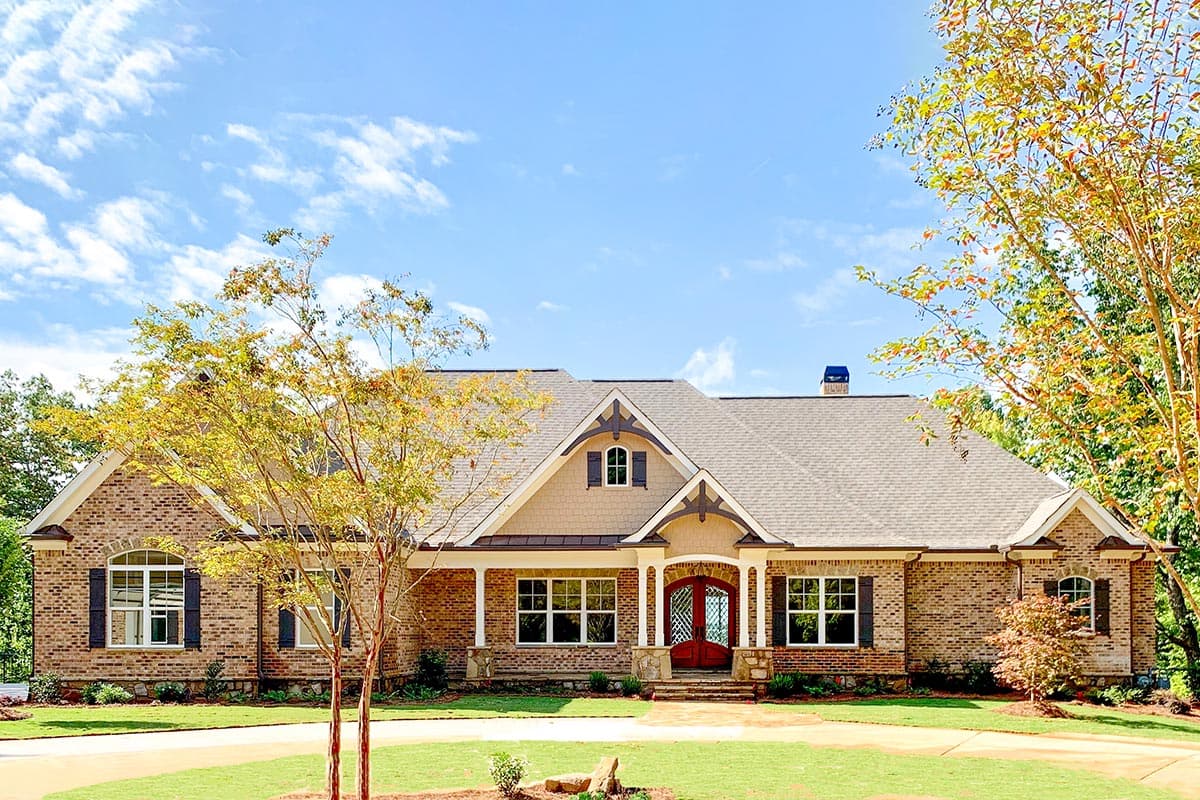 House plan exterior: One-story brick home with a covered porch, dormer window, gables, and a double-door entry.