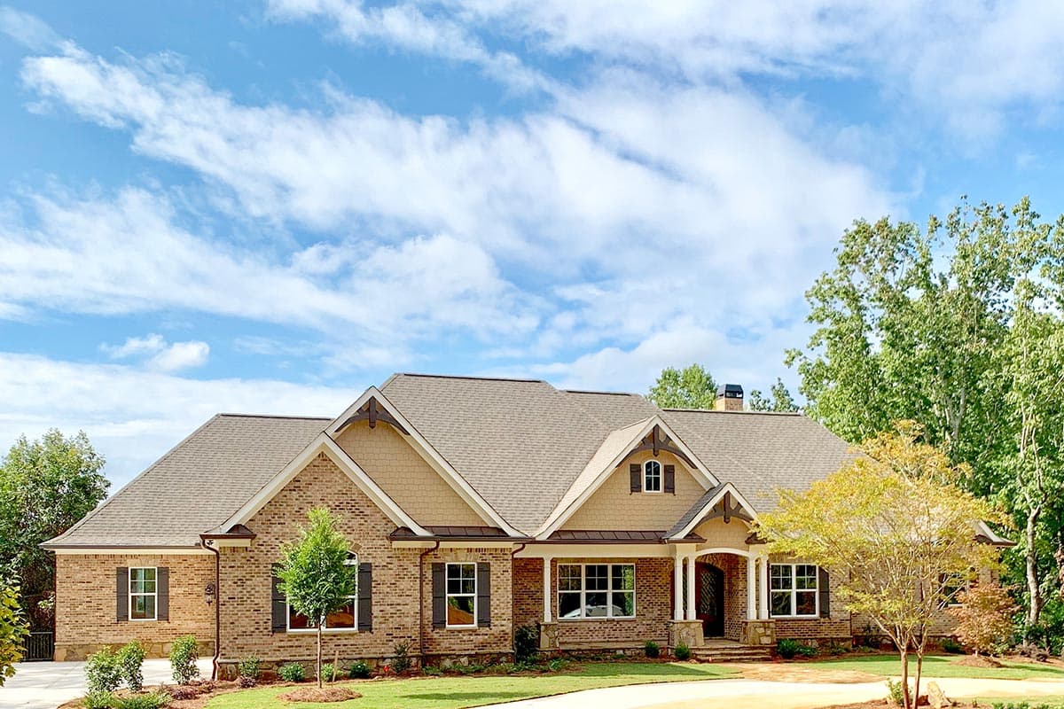 House plan exterior with brick facade, gabled dormers, and covered entry porch with stone accents.