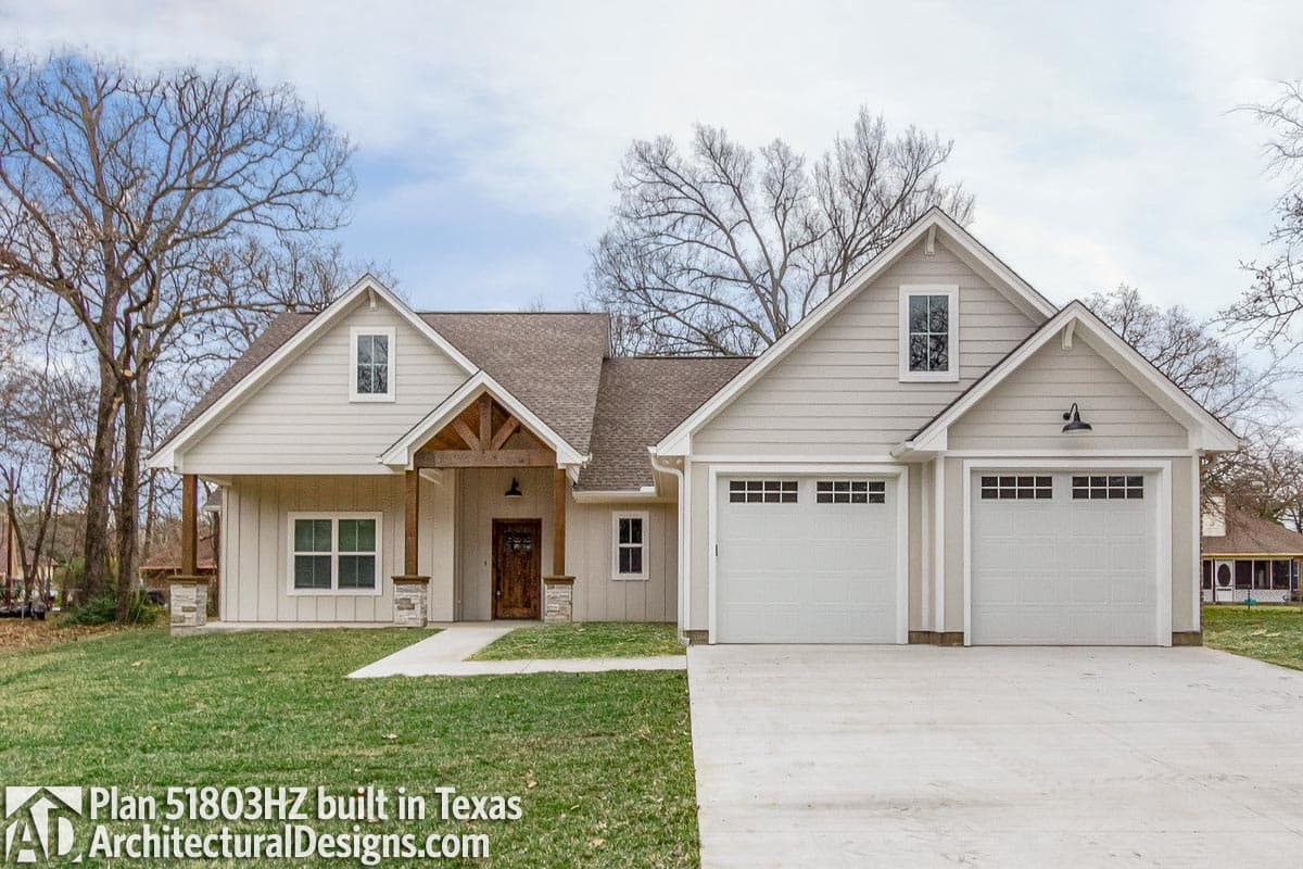 House plan exterior: Craftsman style, one story with prominent gabled entry, stone-clad porch supports, and a three-car garage.