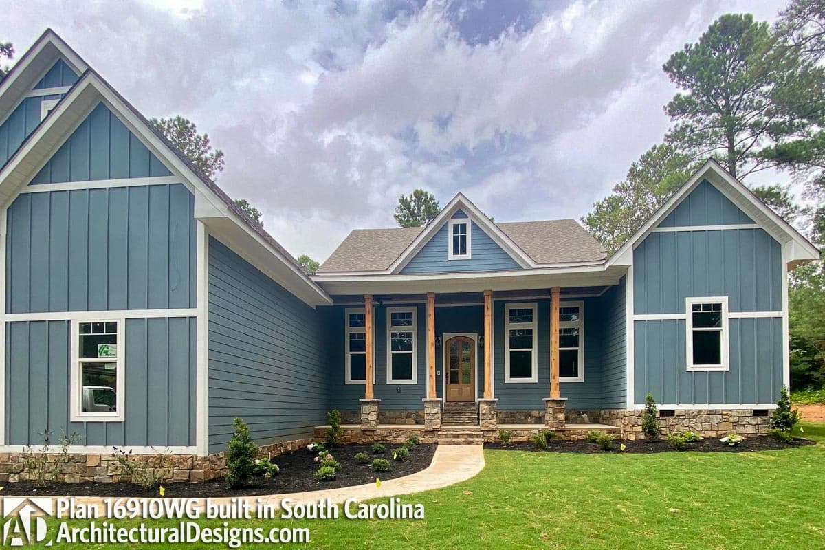 House plan exterior: Ranch style with prominent gabled dormers, covered porch supported by wood columns, and stone accents.