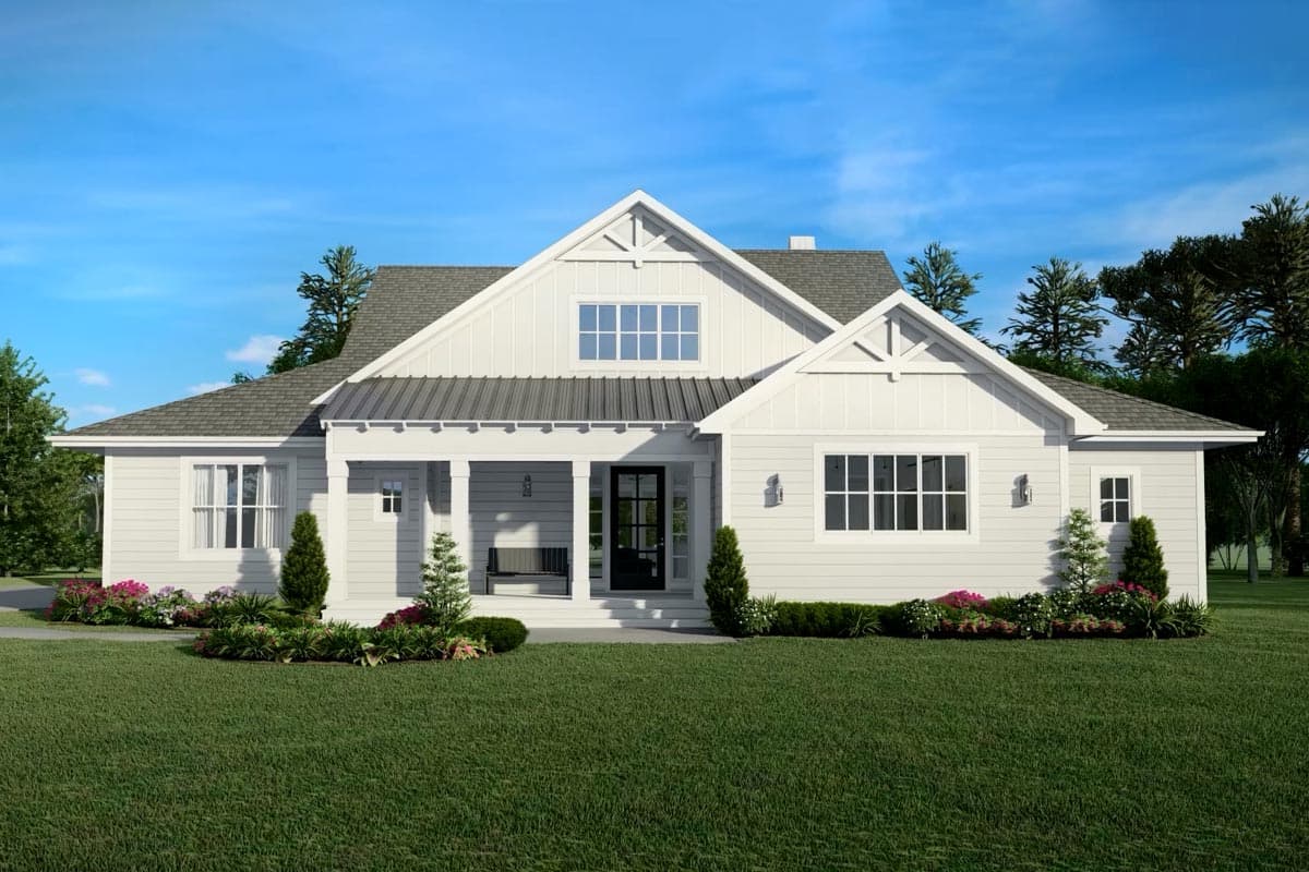 A white, farmhouse-style home with a black front door, porch swing, and manicured lawn. The home has a gabled roof and sits under a blue sky.