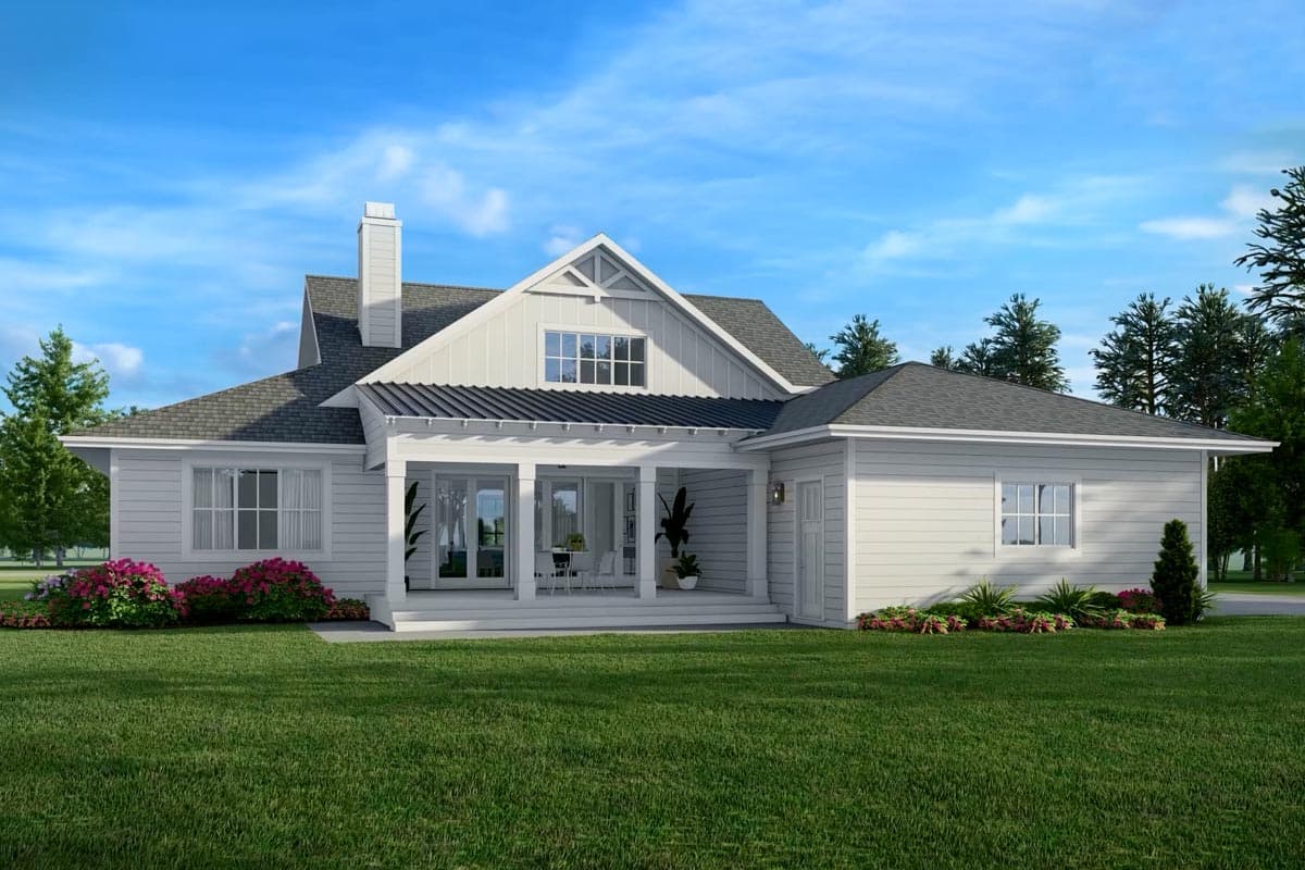 Exterior view of a modern white house with a covered porch and manicured lawn under a blue sky, surrounded by trees and greenery.