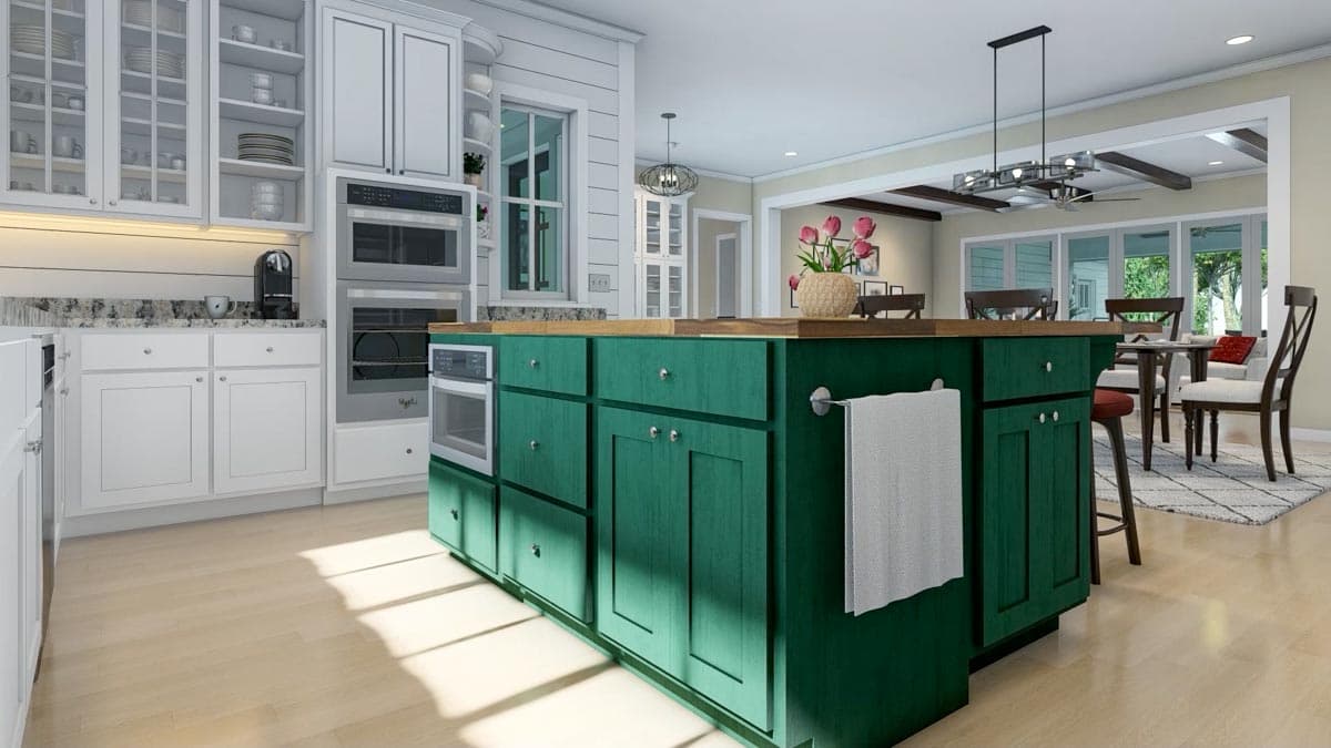 A modern kitchen with white cabinets and a striking emerald green island. A towel hangs from the island, and a dining area is visible in the background.