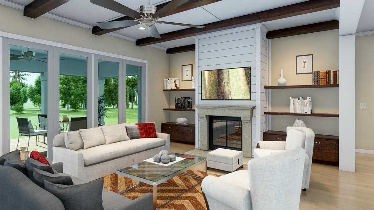 A modern living room with large windows overlooking a patio. The room features a fireplace, ceiling fan, and comfortable seating.