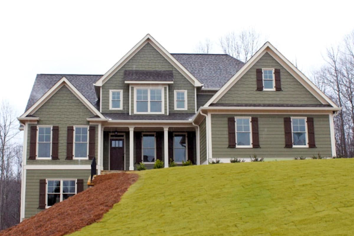 House plan exterior: Two-story home with gable rooflines, front-facing dormers, and a covered front porch with white columns.