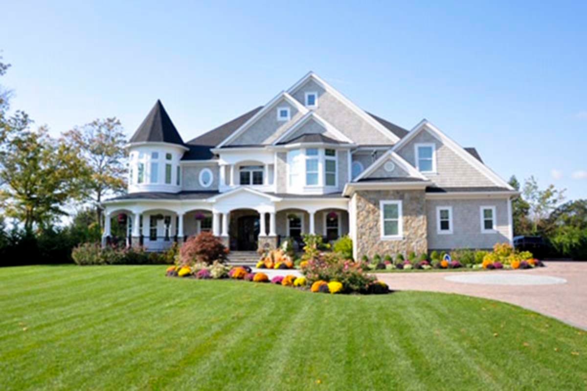 House plan exterior: Two-story home with wrap-around porch, bay windows, stone facade, and conical tower.