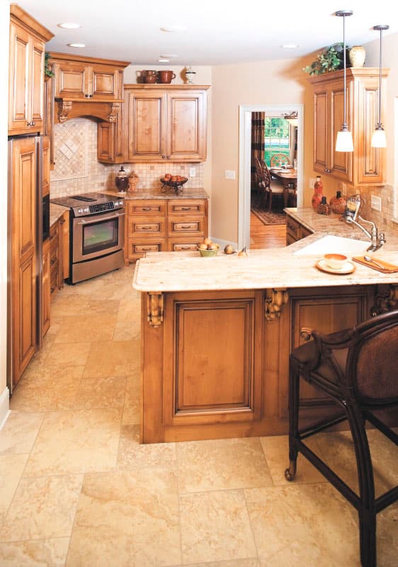 Kitchen with light wood cabinets, granite countertops, stainless steel range, and center island with bar seating.