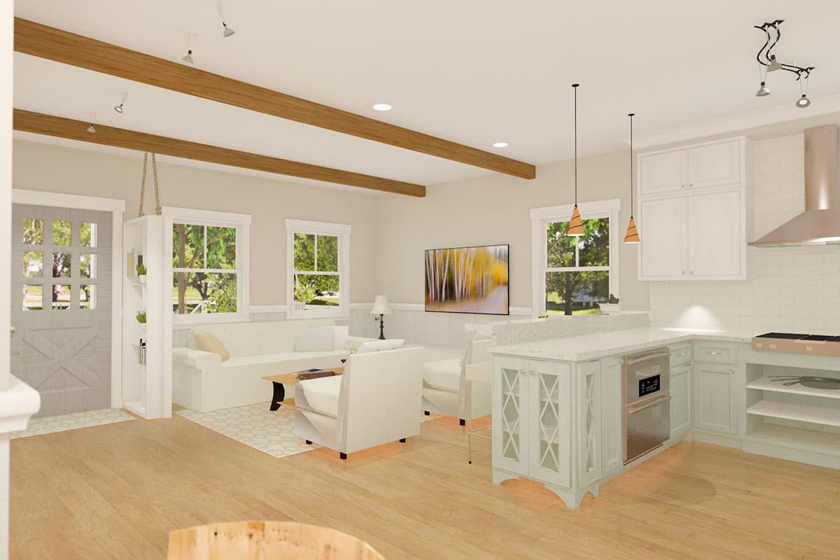 Interior view of living area and kitchen with wooden beams, island, white cabinets, and fireplace.