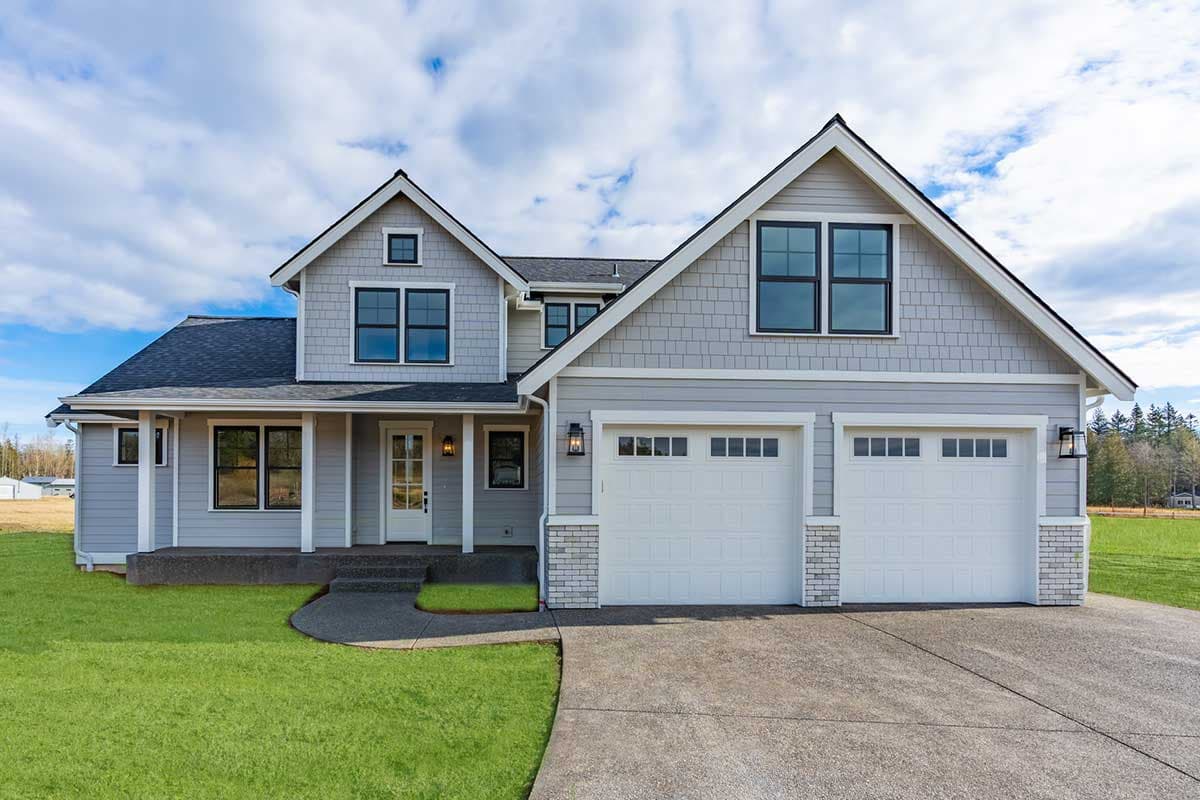 House plan exterior. Two-story, Craftsman-style home with gabled roof, covered porch, and a two-car garage with dormers.