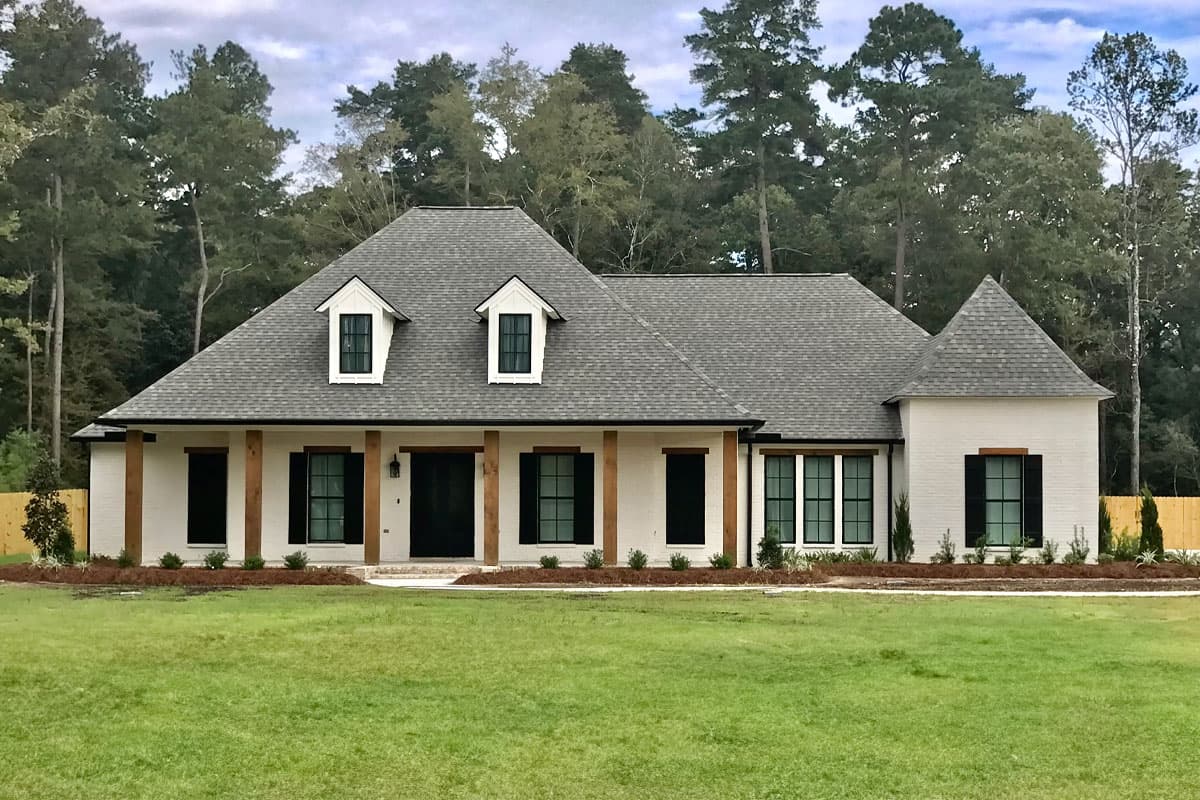 House plan exterior: Modern Farmhouse style, one story, with a covered porch, gable dormers, and exposed wooden beams.