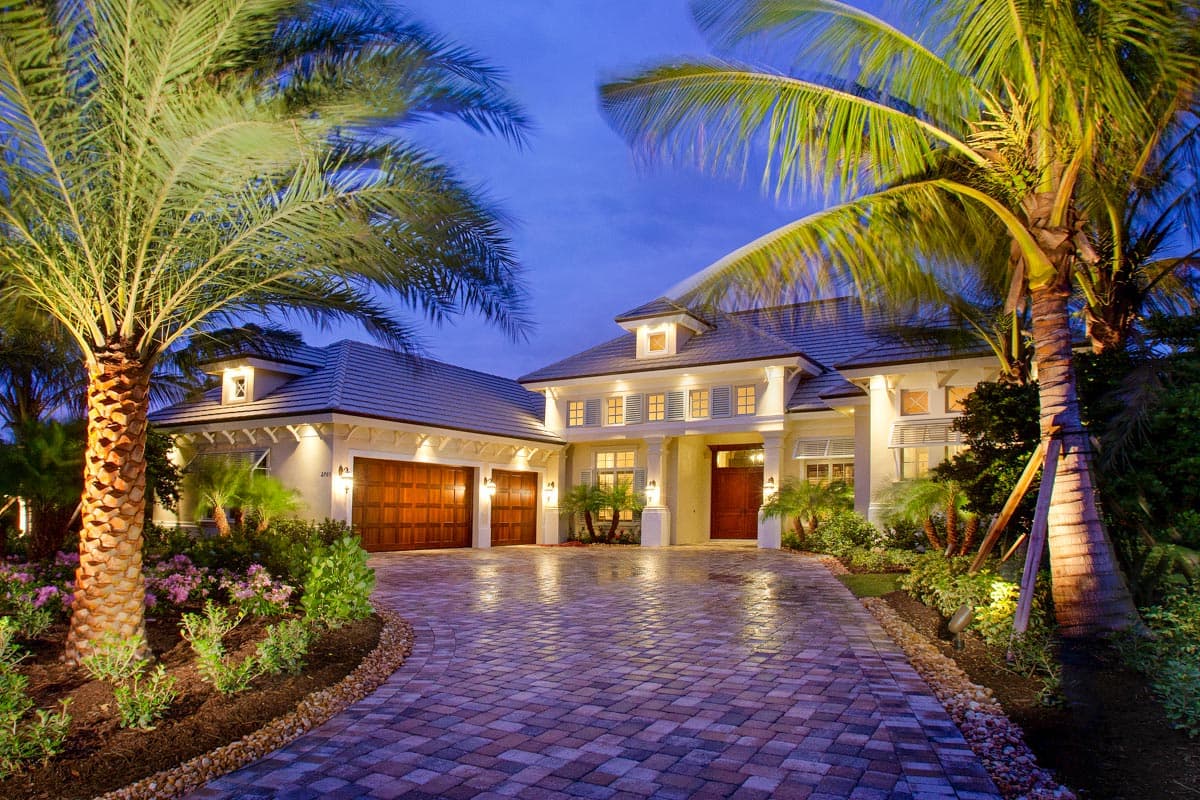 House plan exterior. Two-story, coastal style. Features include dormers, a front-entry portico, and a multi-car garage with wood doors.
