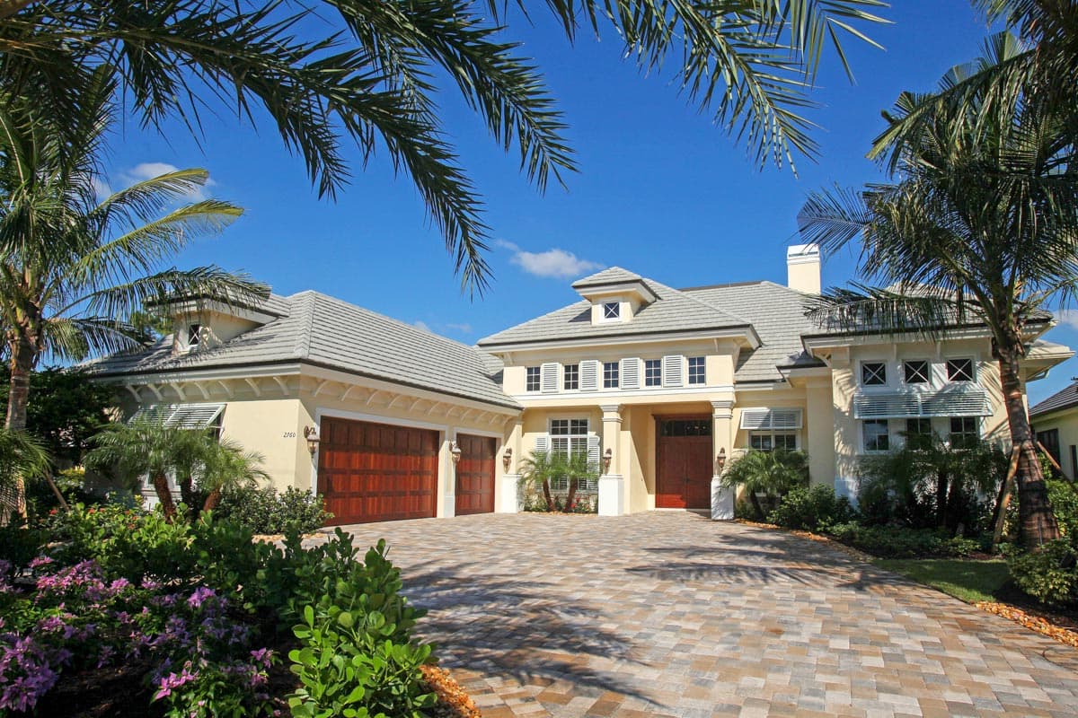 House plan exterior: Two-story residence with a wide paver driveway, three-car garage, covered entry, and hipped roof.