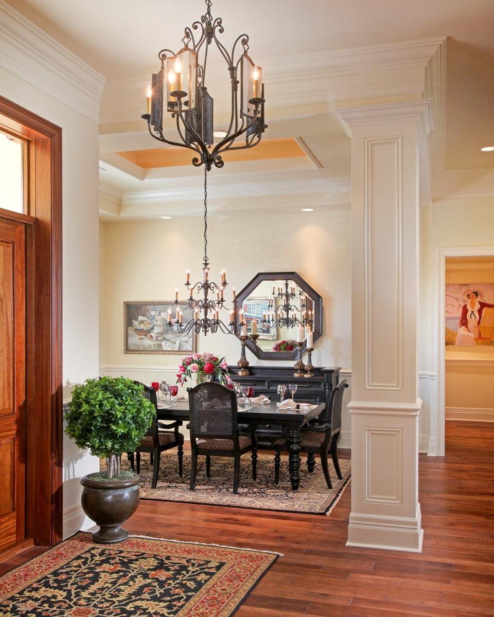 Interior view of a formal dining room with a table, chairs, ornate chandelier, and decorative molding.