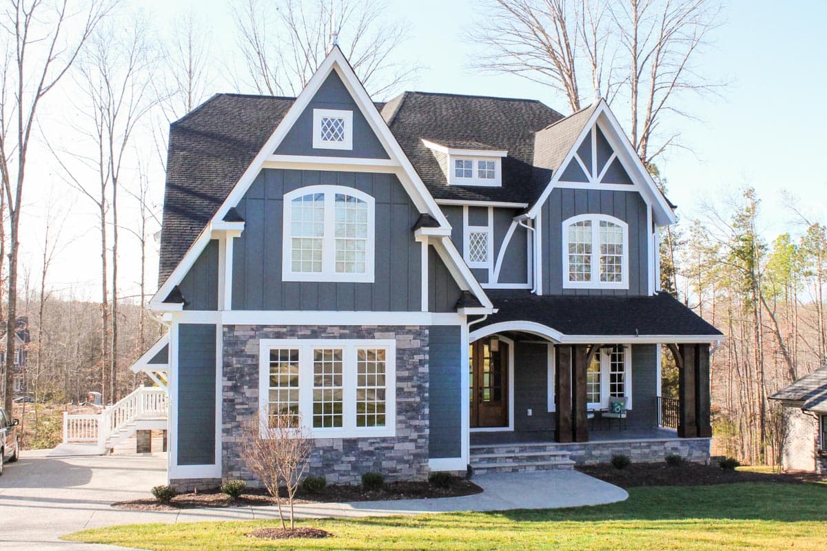 Craftsman style house plan exterior with stone accents, gables, arched windows, and a covered front porch with wood columns.
