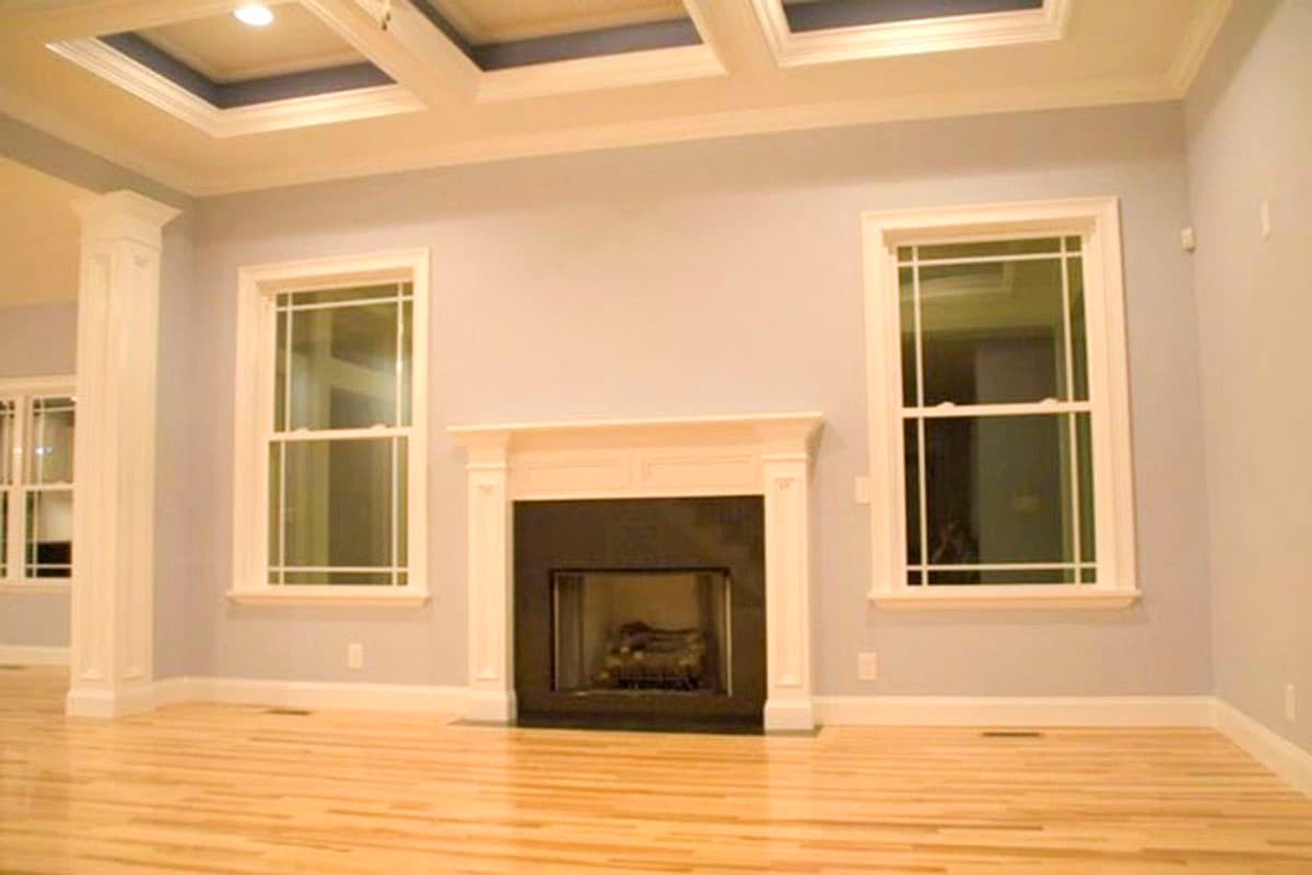 Interior view of living room with fireplace, double-hung windows, and coffered ceiling.