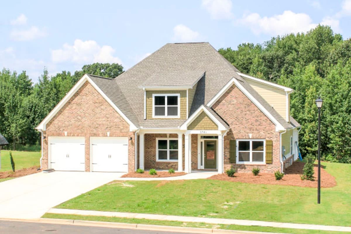 House plan exterior: Two-story brick home with a two-car front-entry garage, covered porch, and prominent gables.