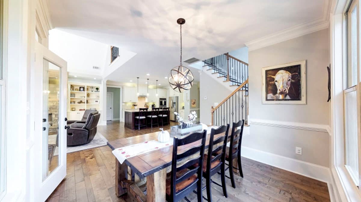 Open concept dining area and kitchen with island, leading to living room with built-ins and fireplace.