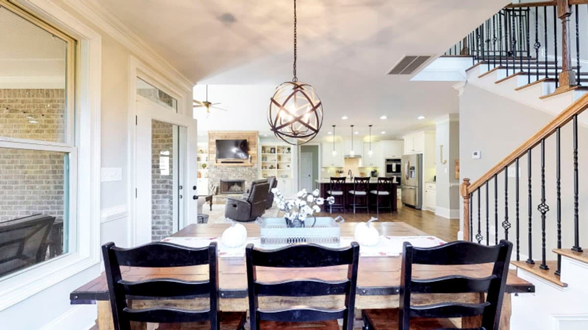 Dining area with staircase, leading to open living room with fireplace and kitchen island.