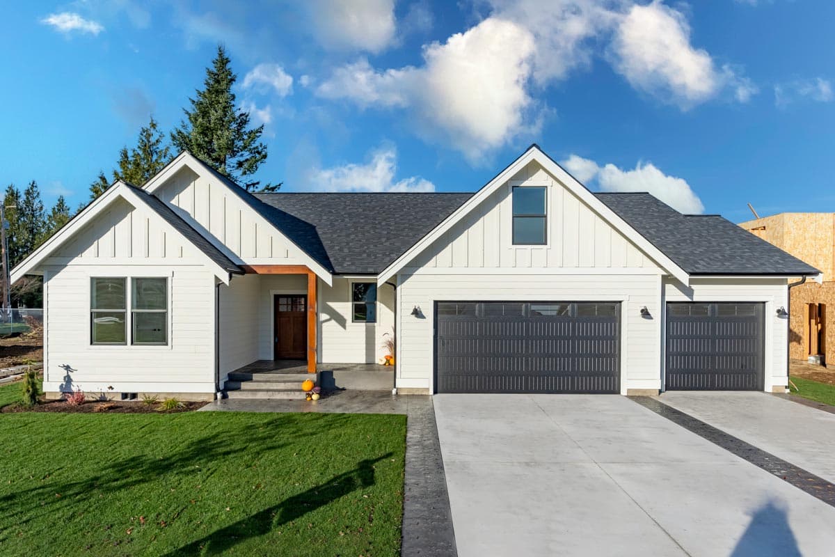 House plan exterior with board and batten siding, Craftsman style, two-car garage, and gabled roof with dormer window.