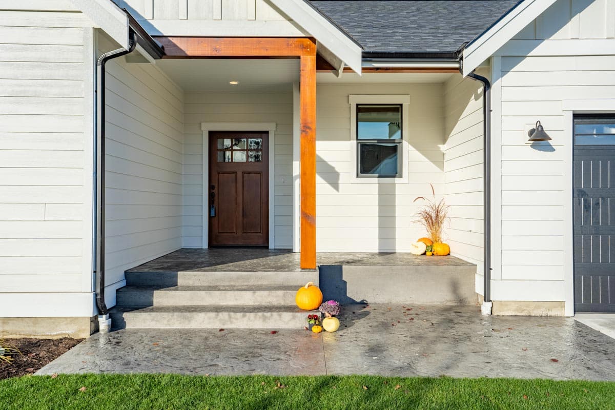 House plan exterior with wood door, wood support beam, pitched roof, and garage.